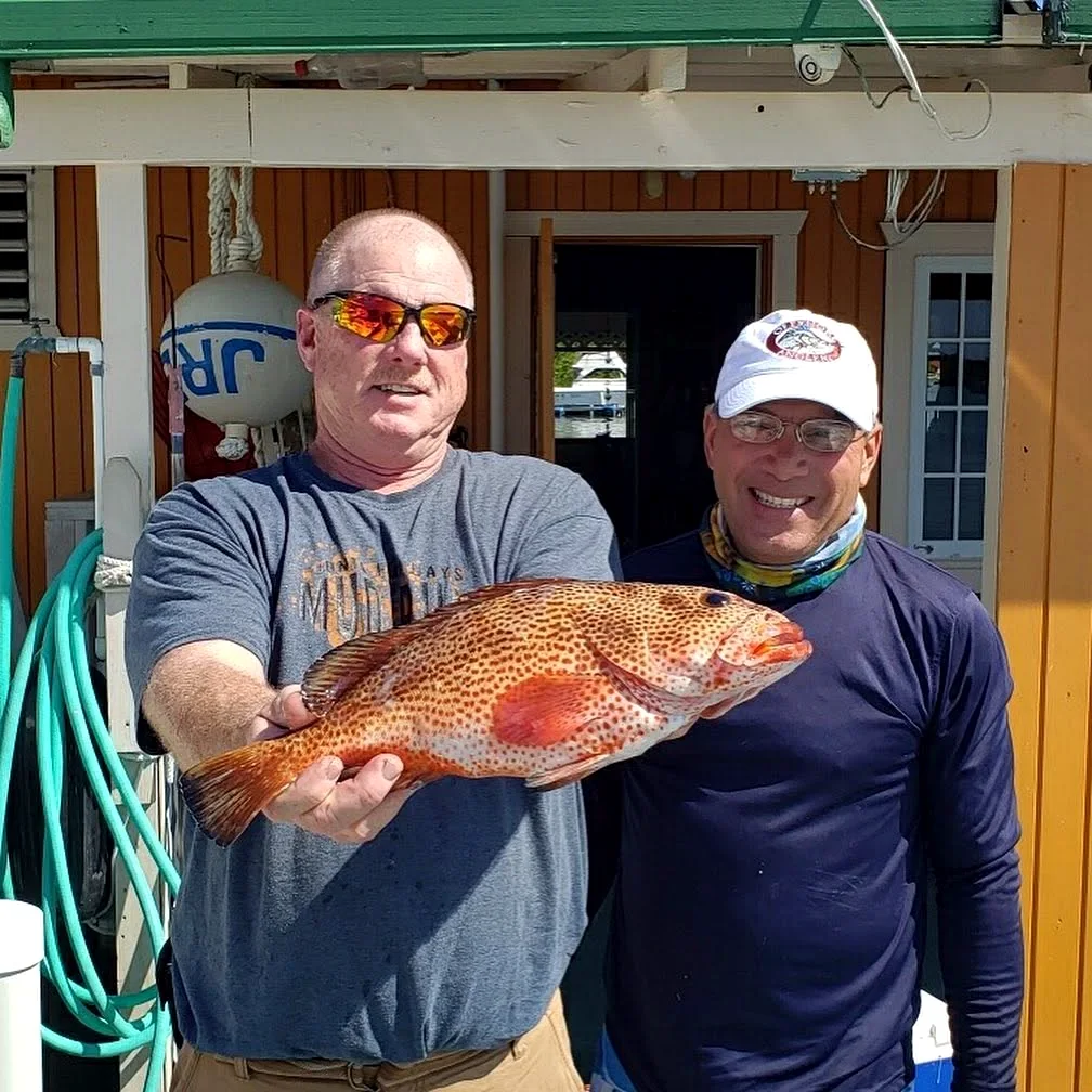 A guest and Captain Frank with a grouper